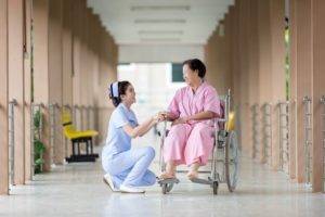 A disabled woman on a wheelchair with a nurse beside her.