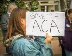 A protester carrying a "save the Affordable Care Act" placard.