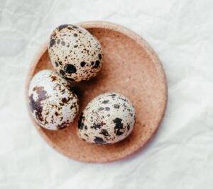 3 quail eggs in a saucer.